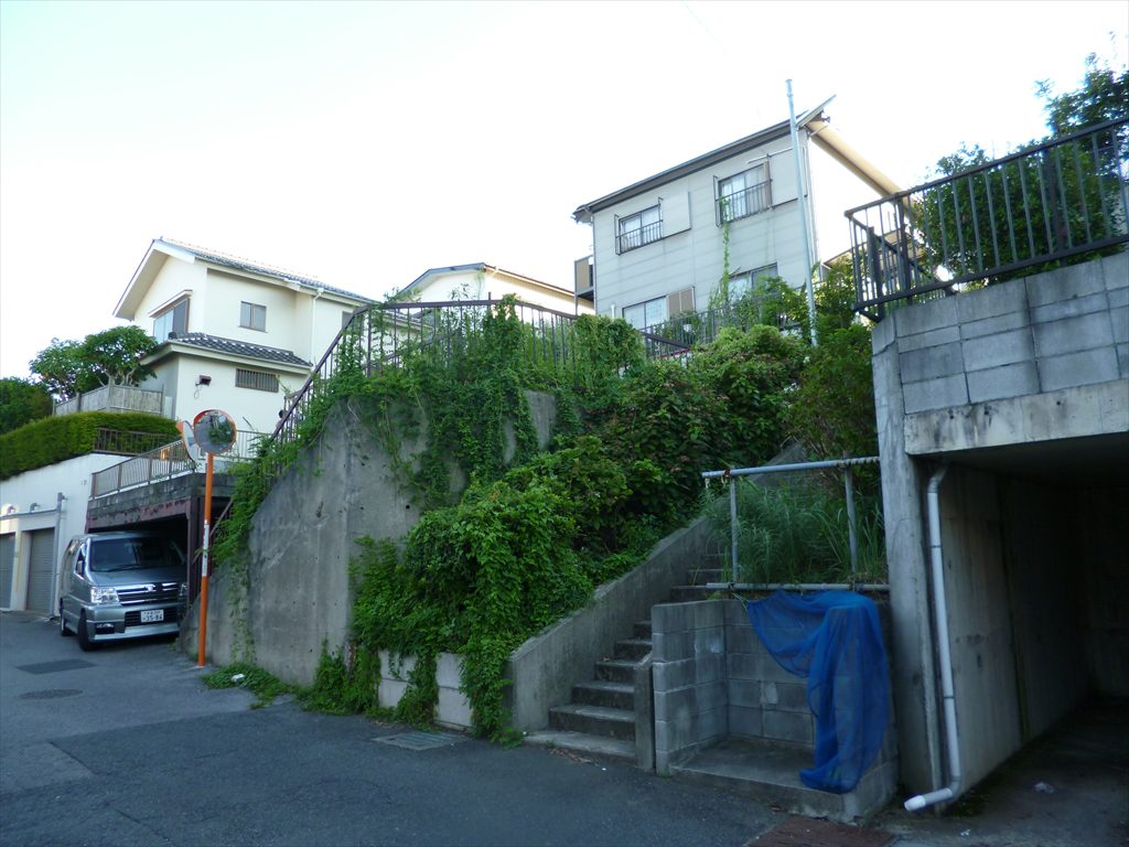 3.5m高のコンクリート擁壁付の土地の左側には鉄骨造の人工地盤の車庫スペースがあり、その敷地のさらに上には3.5m擁壁付の隣地があります
