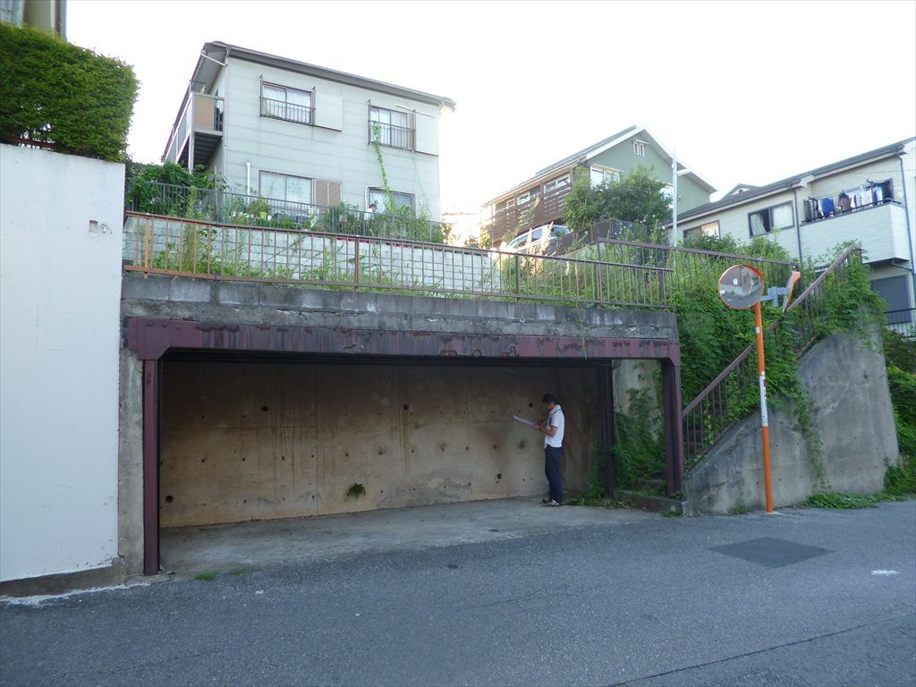 3.5m高のコンクリート擁壁付の土地の左側には鉄骨造の人工地盤の車庫スペースがあり、その敷地のさらに上には3.5m擁壁付の隣地があります