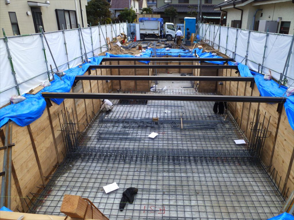 砂混じりシルト質の土地での地下室工事は山留を慎重に行う必要があります。また山留杭が傾斜しないように杭頭に倒れ止めを施工しています。道路位置からこの地下室にスロープで車や自転車を降ろしてくる大型の自家用駐車場を作っています